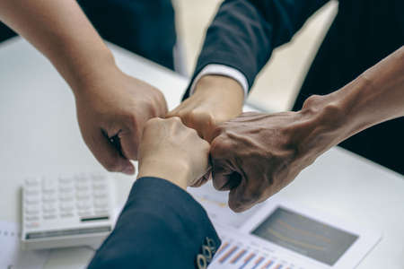 Successful colleagues put their naughty hands with fists together in the financial business idea office.の写真素材