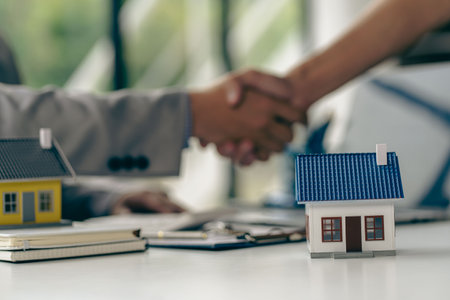 business people shaking hands in the office Sign a home purchase contract between the buyer and the seller. Real estate agent after signing documents and house plans on wooden tablの写真素材