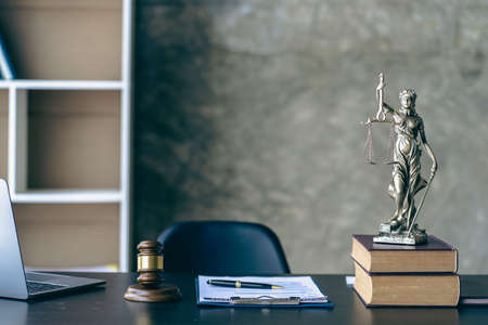 The concept of the law with a judge's hammer and scales. Goddess of Justice with laptop and tiger skins on lawyer's desk.の写真素材