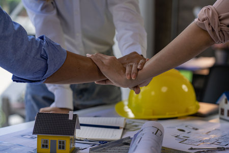 Engineers, architects, construction workers shake hands after project planning contract at desk in...
