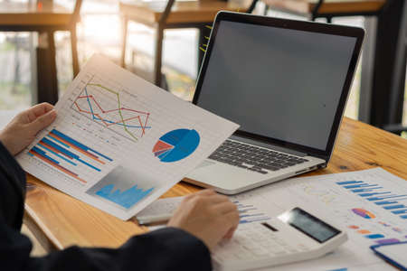 businessman holding pen with laptop graphing documents financial calculator deck for calculations...