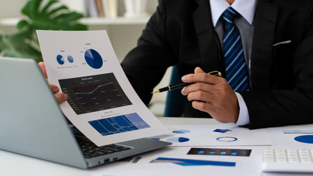 businessman holding pen and pie chart document showing company financial data He sits in a private...