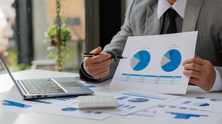 businessman holding pen and pie chart document showing company financial data He sits in a private...