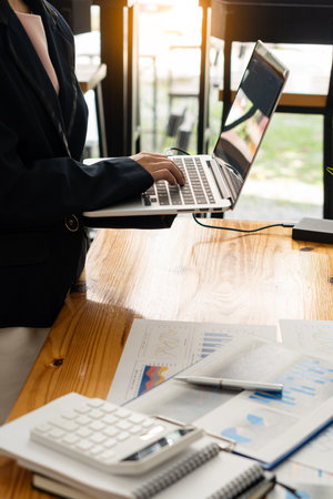 Businessman analyzing finances with documents, graphs, accounts and laptop computers. calculator on the desk in the office vertical pictureの写真素材
