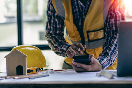 engineer working in office draw a construction project An architect's hand-drawn print engineer discusses floor plans over architectural blueprints at a desk in a modern office.の写真素材