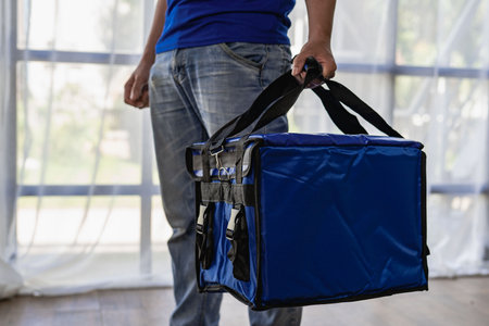 Young man carrying a blue bag, express food delivery, service conceptの写真素材