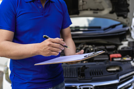 A young man checks the oil level and repairs the car before leaving.の写真素材