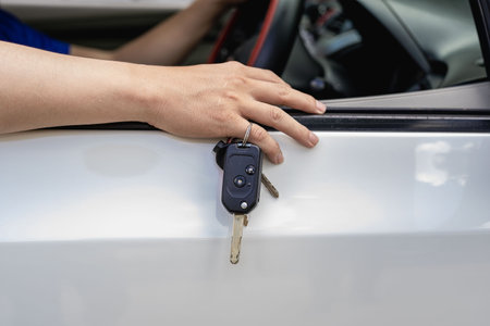 The new car owner put the key on his finger and put it on the car door.