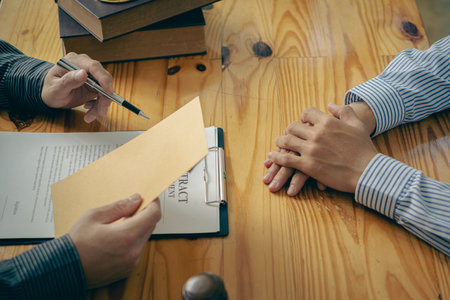 Businessman and lawyer discussing contract documents with golden scales, god of justice, yellow on wooden table in law office, advice, justice conceptの写真素材