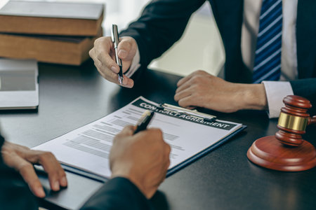 Businessman and lawyer discussing contract documents with golden scales, god of justice, yellow on wooden table in law office, advice, justice conceptの写真素材