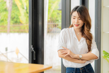 Smiling Asian woman standing with her arms crossed looking at the camera at work
confidentlyの写真素材