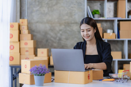Beautiful Asian girl freelance SME business online shopping working on computer, laptop, smartphone with parcel box at home - online SME business idea and delivery.の写真素材