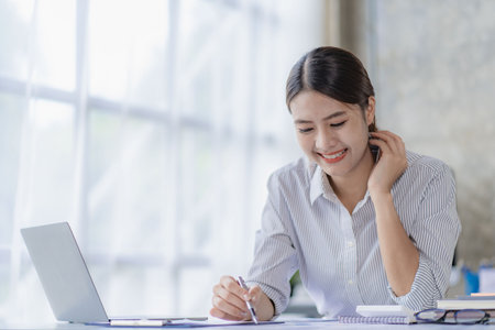 Asian woman working using laptop computer in modern office make an account analysis report real estate investment information tax and financial system conceptsの写真素材