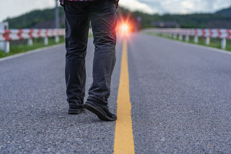 The human leg walked along the path in the bright orange light of day. The man's feet moved slowly.の写真素材