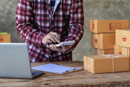 Young Startup Small Business SME Owner Male Entrepreneur Check online orders to prepare, pack boxes,...