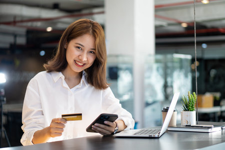 Woman holding smartphone and credit card, shopping online and paying with card.の写真素材