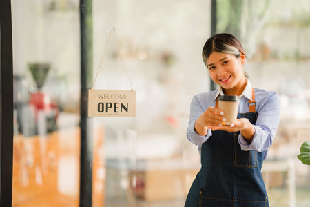 Asian women set up a sign to open a shop to welcome customers at a coffee shop. small business owner...