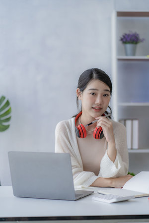 Cute Asian College Student Studying Online With Laptop
Put on headphones to study on the Internet at home.の写真素材