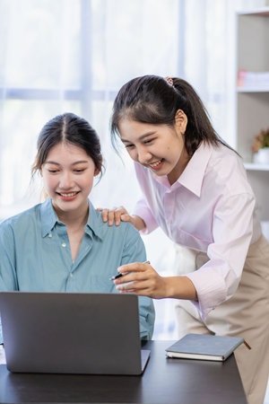 Two young Asian women discuss the concept of a new start-up project. analysis of financial planning and statistics and investment market on laptop computersの写真素材