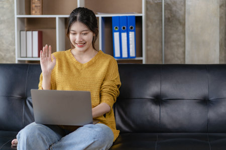 Attractive Asian woman rejoicing on her success using laptop to work online at home.