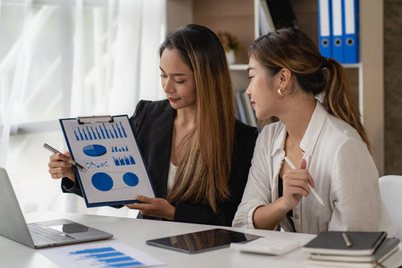 Two Asian businessmen or accountants brainstorm financial charts.
Two Asian female financial advisors or analysts work. Discuss financial reports together.の写真素材