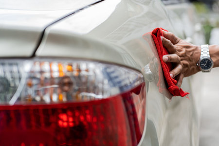 young man checking a car clean the car Young Asian man holding a microfiber in his hand and polishing a car. Car inspection and maintenance services.の写真素材