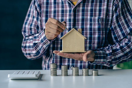 Calculator house simulator and pile of finance coins, mortgages, loans and finance.
Businessman holding a house, saving money idea to buy real estate, save money, plan to save monの写真素材