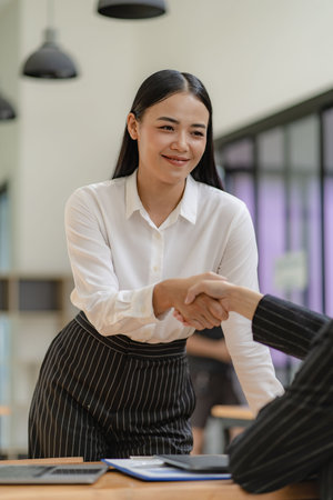Asian business women shaking hands Two young business women shaking hands with a smile. Close deal or partnership concept.の写真素材