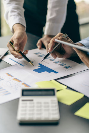 close-up group of business people with financial graphs and money pens An accountant holding a pen pointing to a chart of documents for a team meeting in the office Finance and Accの写真素材