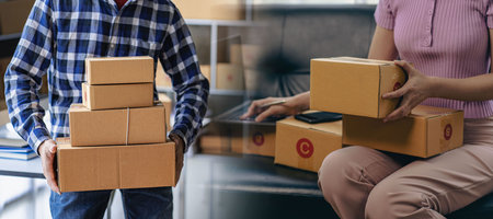 Online business idea, young sme entrepreneur, working from home with laptop and smartphone to take orders and deliver parcels.の写真素材