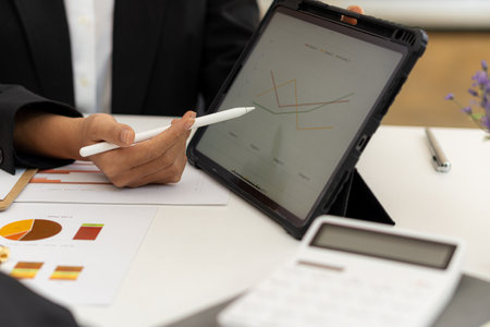 Businessman using a tablet to analyze company financial budget report graphs and cost of work...