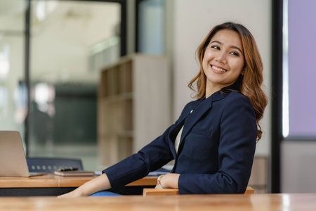 An Asian female accountant sits at a desk with a laptop working and calculates a financial graph showing results about successful investment planning.の写真素材