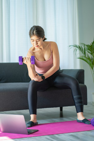 Asian woman exercising using dumbbells Beautiful woman practicing yoga, meditating, indoors at home, wearing sportswear, taking a full body photo and practicing meditation. healthyの写真素材