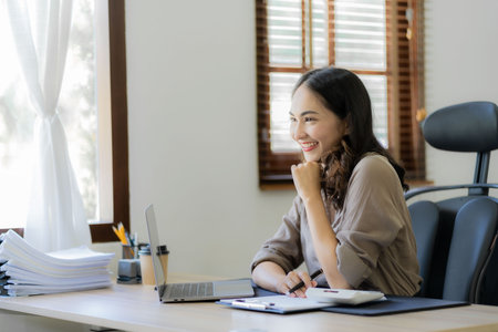 Asian female accountant working to analyze technical price charts and indicators with the Accounting or Savings business team.の写真素材