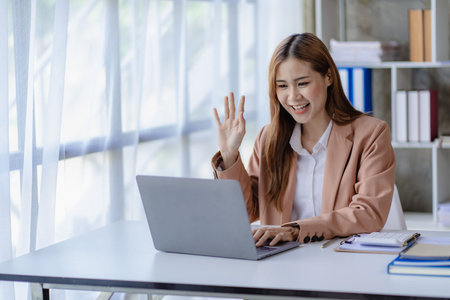Beautiful Asian businesswoman working with laptop computer at office desk. Female entrepreneur typing financial documents. Check email at work. Financial accounting concept.の写真素材