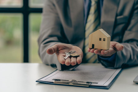 Businessman holding keys and handing over house to customer, real estate agent handing over keys to home buyer after contract of purchaseの写真素材