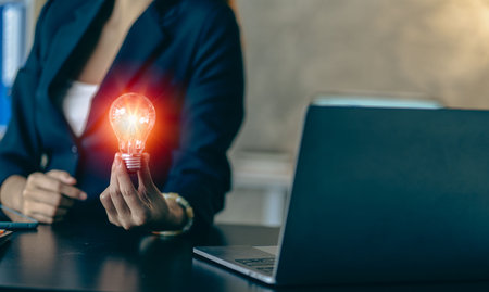 Innovate through ideas and inspiration. Human hand holding a light bulb to illuminate creativity and inspiration of sustainable business development ideas.の写真素材