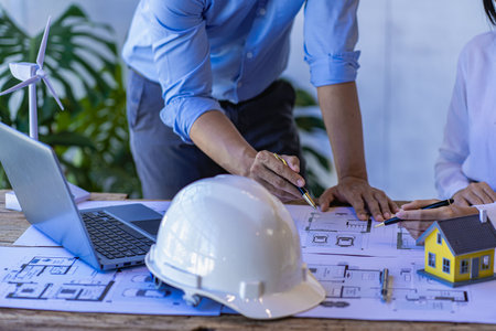 Asian engineer Foreman or leader discussing home solar photovoltaic and wind turbine model in...