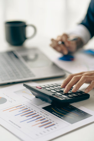 vertical view businessman hand holding a pen using a calculator Work with charts and analyze business strategies. financial statisticsの写真素材
