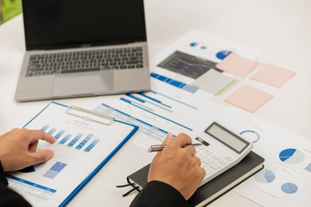 Young businessman working at office with financial documents, laptop, calculator on table Planning to analyze financial reports business plan investment accounting conceptの写真素材