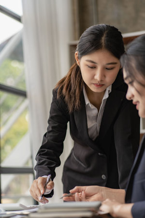 Two young asian accountants working on laptop computer and finance at workplace. Freelance business. Online marketing. ecommerce marketing ideasの写真素材