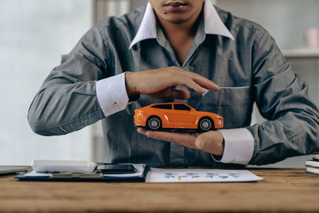 Car insurance. Small orange car protected by businessman hand, warranty, repair. Finance, banking...