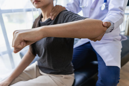 Male therapist treating injured shoulder on female athlete's shoulder Post traumatic muscle rehabilitation, sports physiotherapy, recovery concept.の写真素材