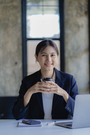 Young successful young asian businesswoman working with smartphone and laptop to contact clients,...