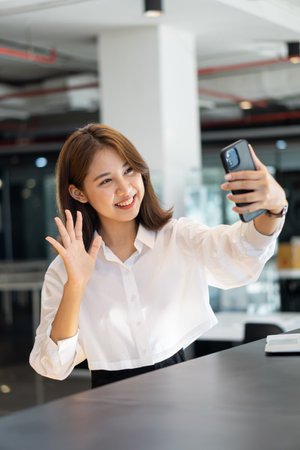 Young Asian woman with big smile using mobile smartphone with social media icons and social network in living room.の写真素材