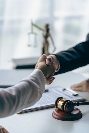 Lawyer shaking hands with client after agreement Gavel Justice hammer on wooden table with judge and client shaking hands after advice in courtroom, notary service conceptの写真素材
