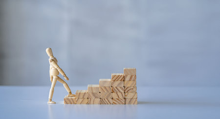 wooden man walking up the career ladder Wooden brick ladder, concept of self-improvement, career, transformation, success step. White background. copy space for adsの写真素材