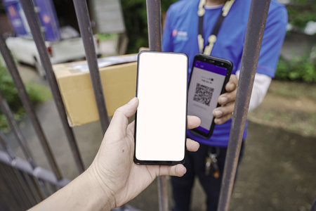 Online shopping concept, hand customer using digital mobile phone, scanning QR code, paying for receiving parcel box from home delivery man. digital payment technologyの写真素材