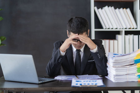 Tired asian young businessman with stacks of paperwork. Busy work, overworked, part time work...
