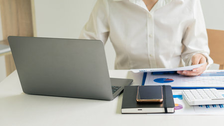 Businessman hands on keyboard of laptop computer showing data analysis graph Businessman working and analyzing financial figures on graph documentの写真素材